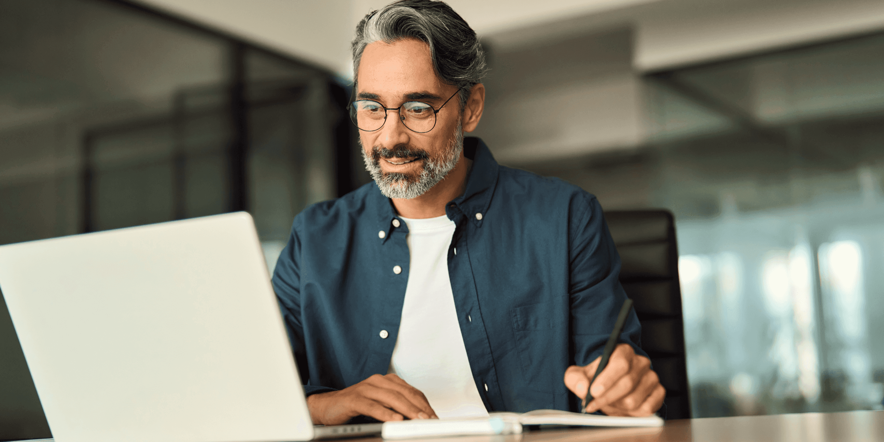 Man inside an office, looking at his laptop