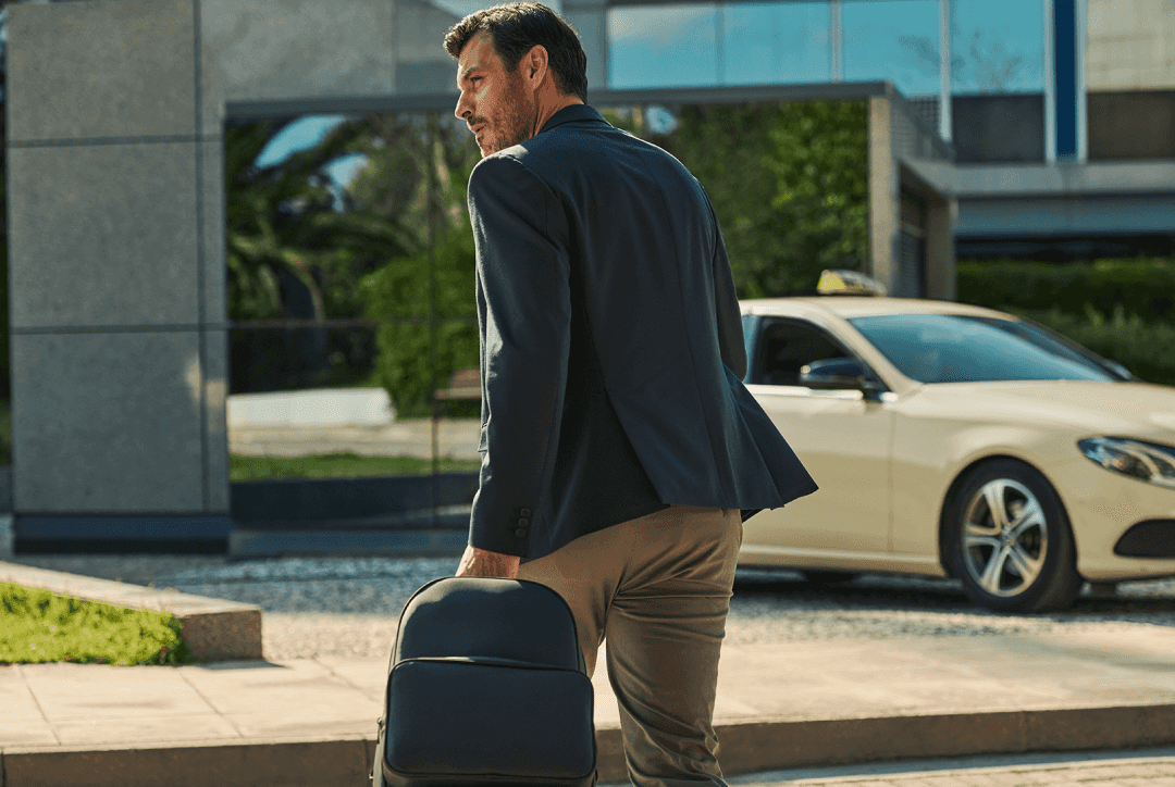 Employee on street with luggage rushing to red FREENOW taxi in background