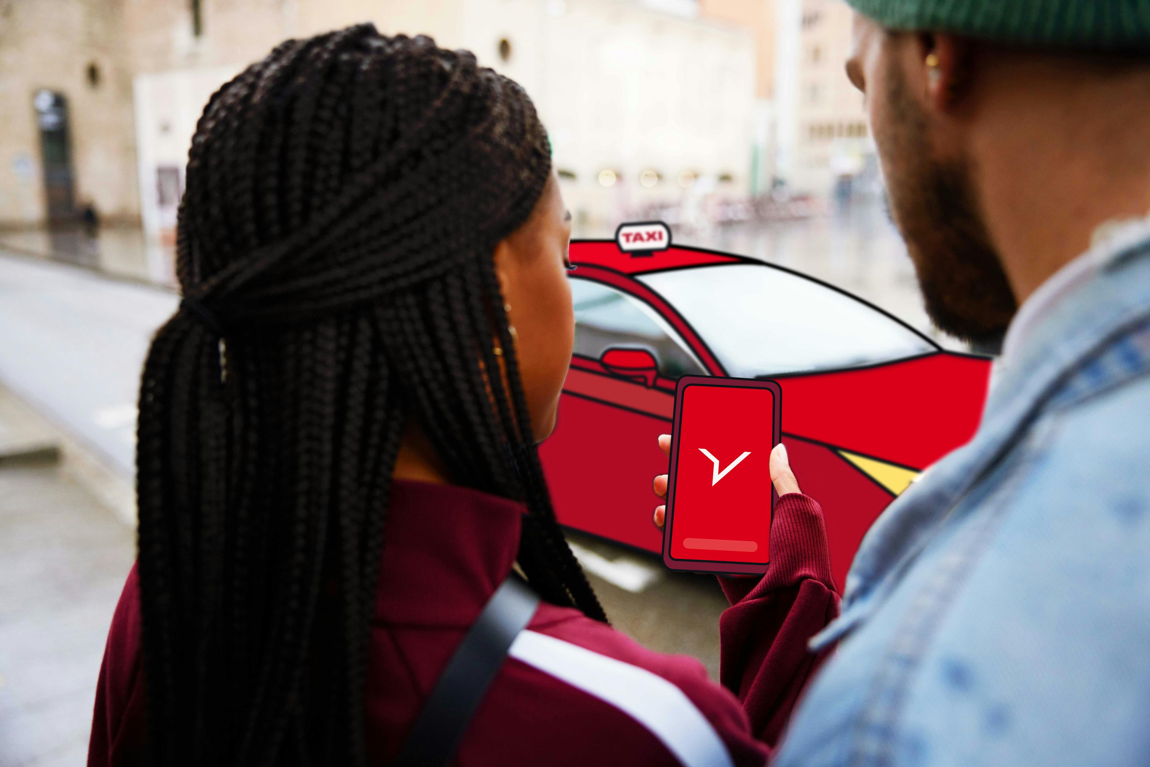 Dwóch podróżujących w interesach patrzy na telefon z logo FREENOW na ekranie i czerwoną taksówką w tle