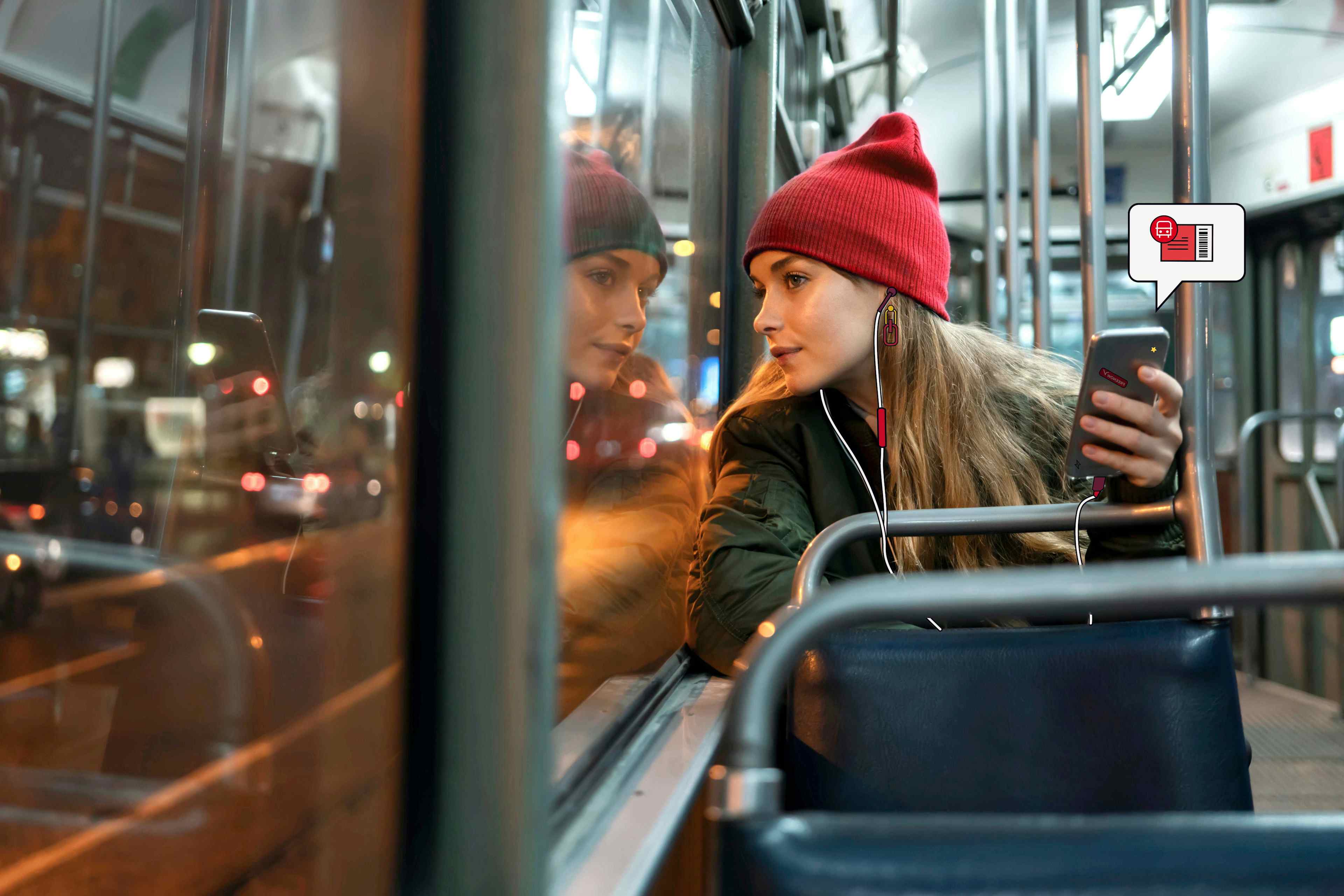 Empleada montada en el autobús sosteniendo su teléfono con el icono de un billete de transporte público asomando el teléfono